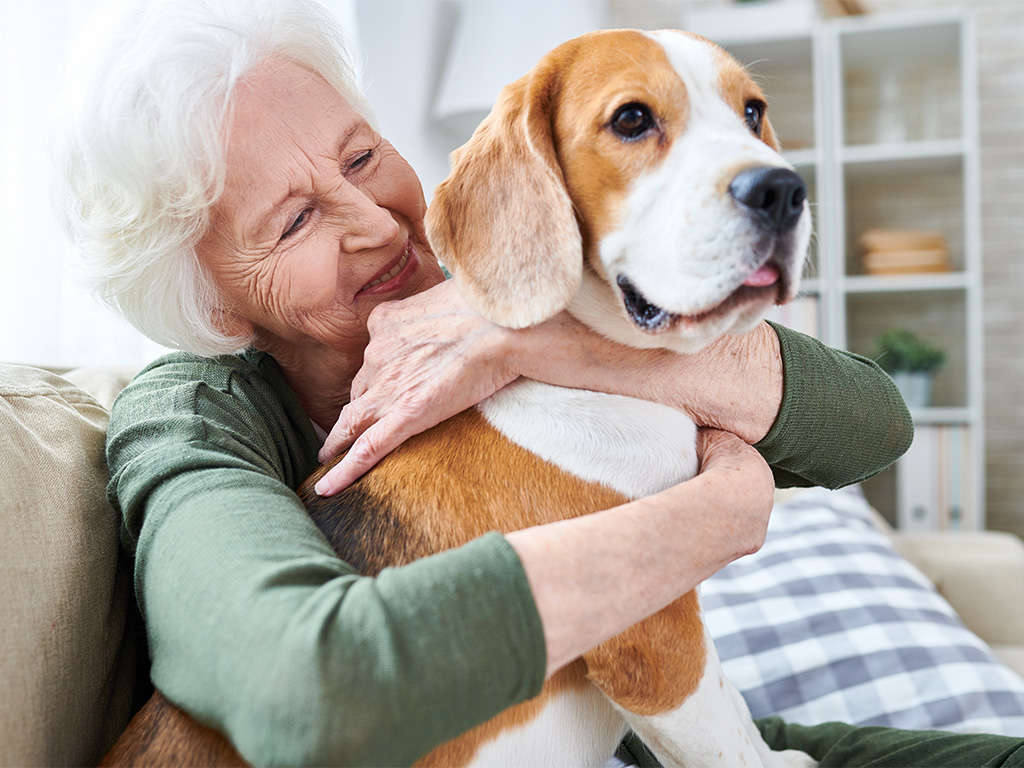 Older Woman Hugging And Smiling At Her Dog